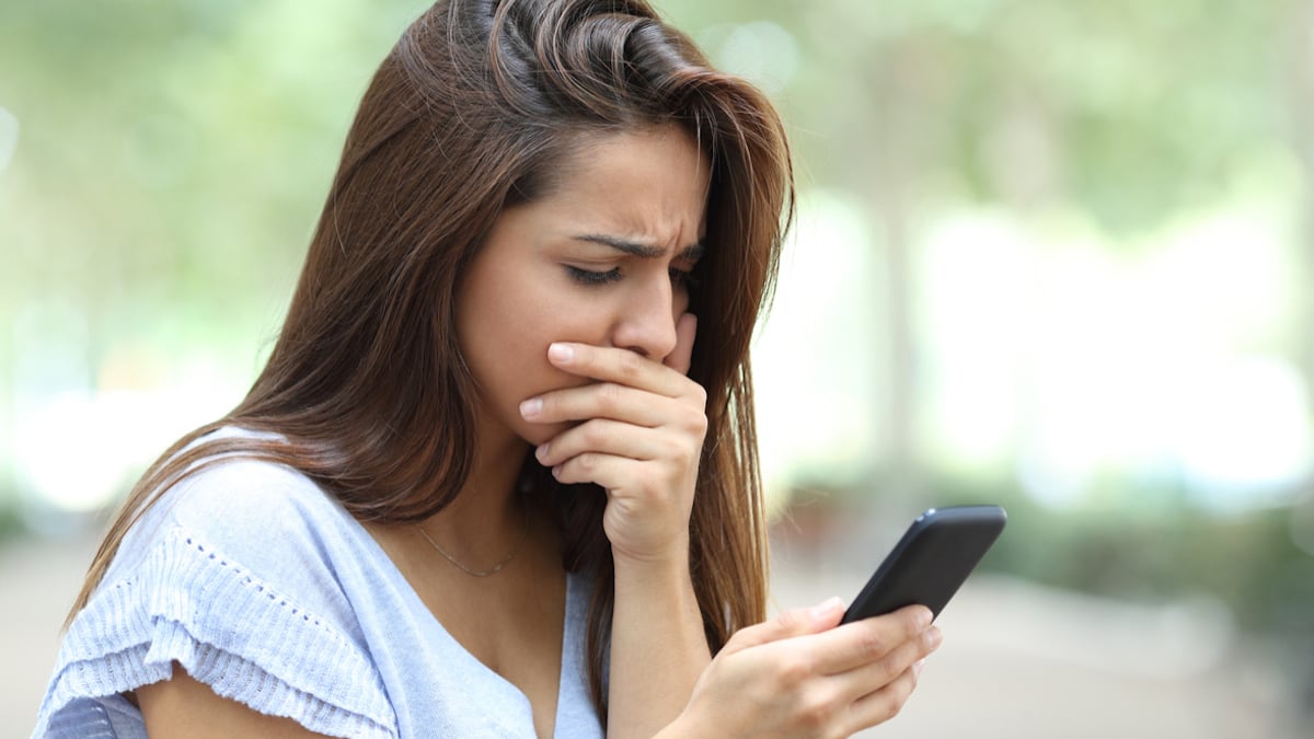 Une femme choquée en train de lire un message sur son portable