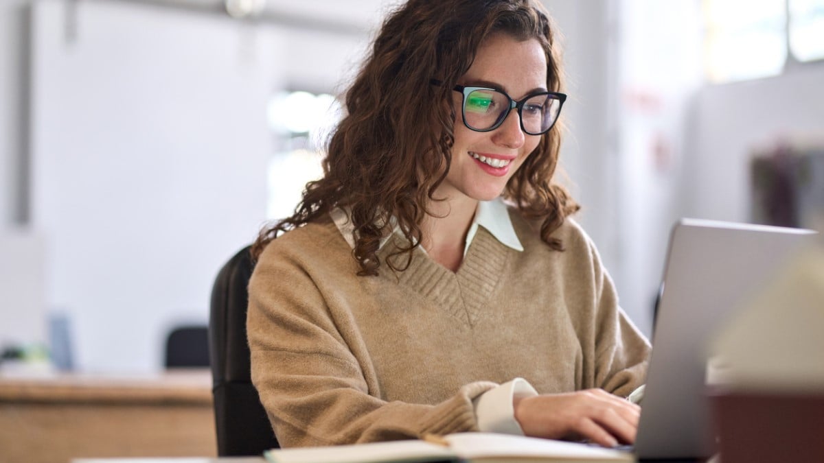 Une femme souriante travaille sur un ordinateur