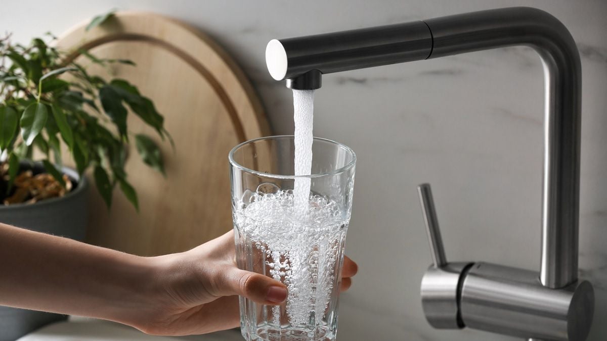 personne remplissant un verre d'eau du robinet