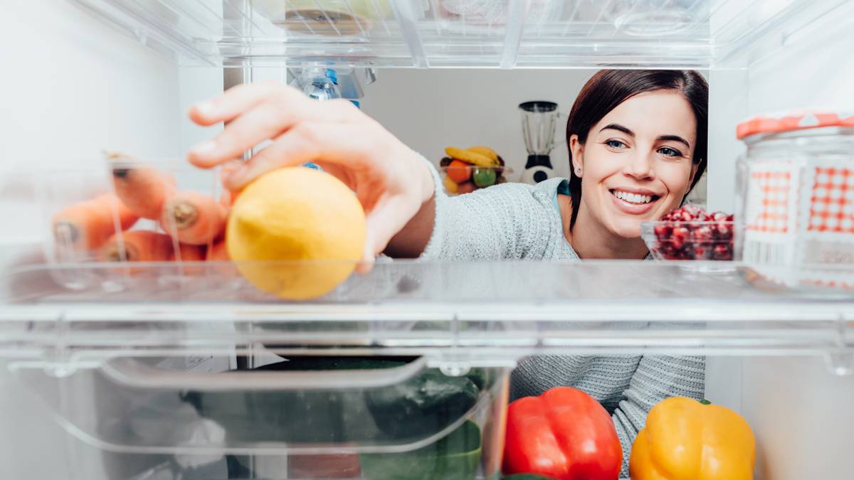 Une femme en train de ranger son frigo