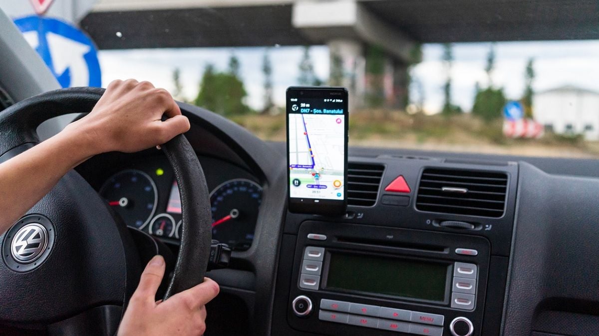 conducteru au volant avec l'application Waze sur le smartphone