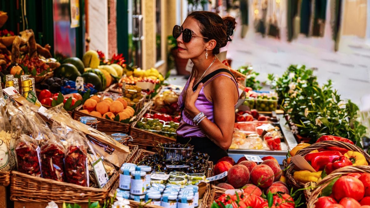 Une femme en train de choisir ses fruits et légumes en été chez le primeur