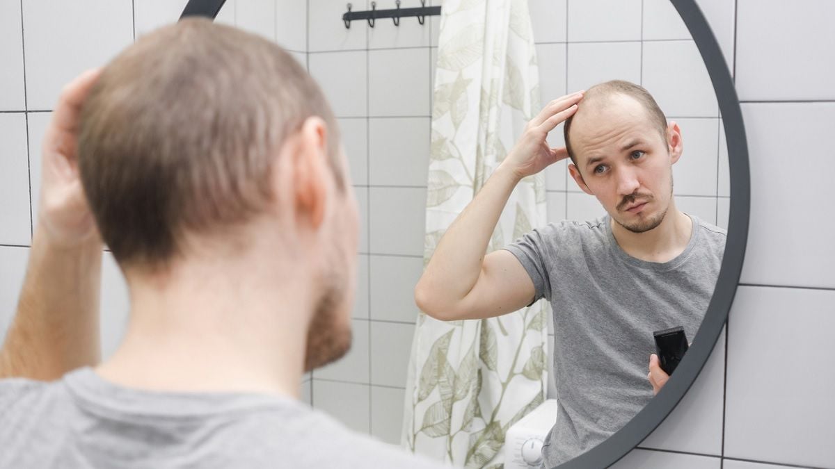 homme avec une calvitie se regardant dans le miroir