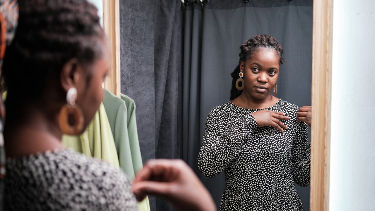 jeune femme essayant une robe dans une cabine d'essayage