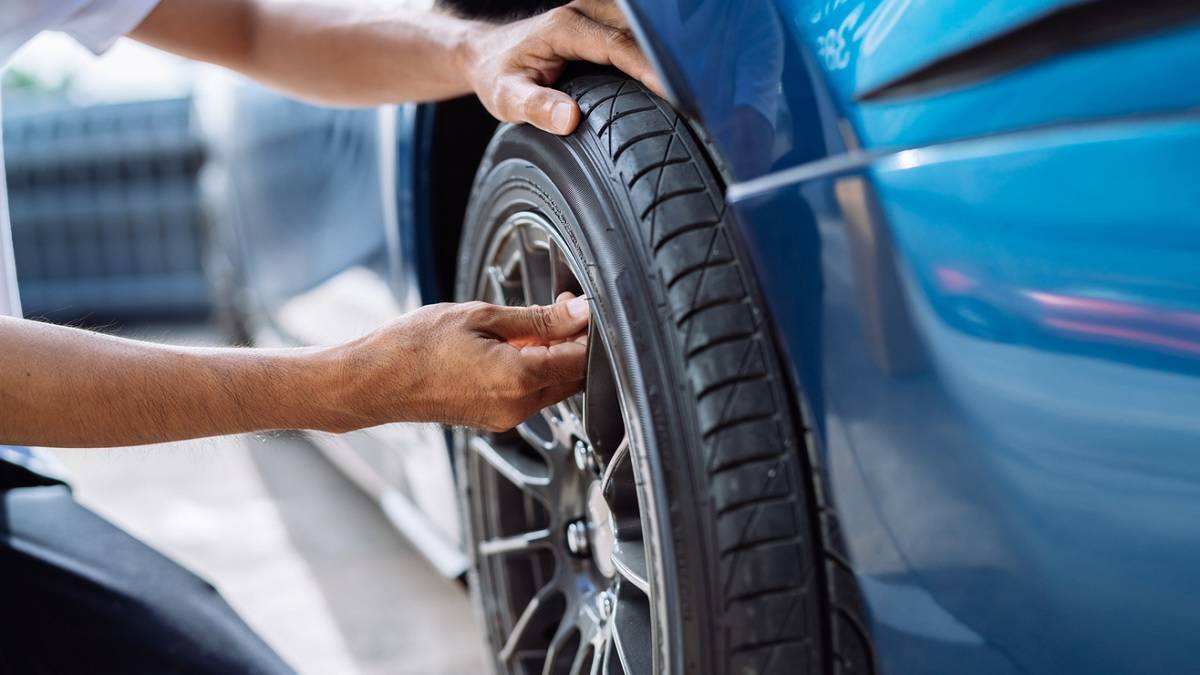 homme vérifiant l'état des pneus de sa voiture