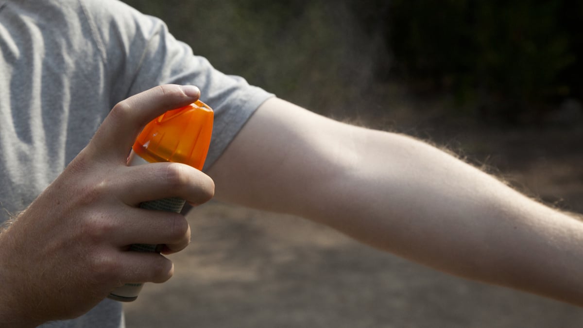 Un homme appliquant du spray anti-moustiques sur son bras 