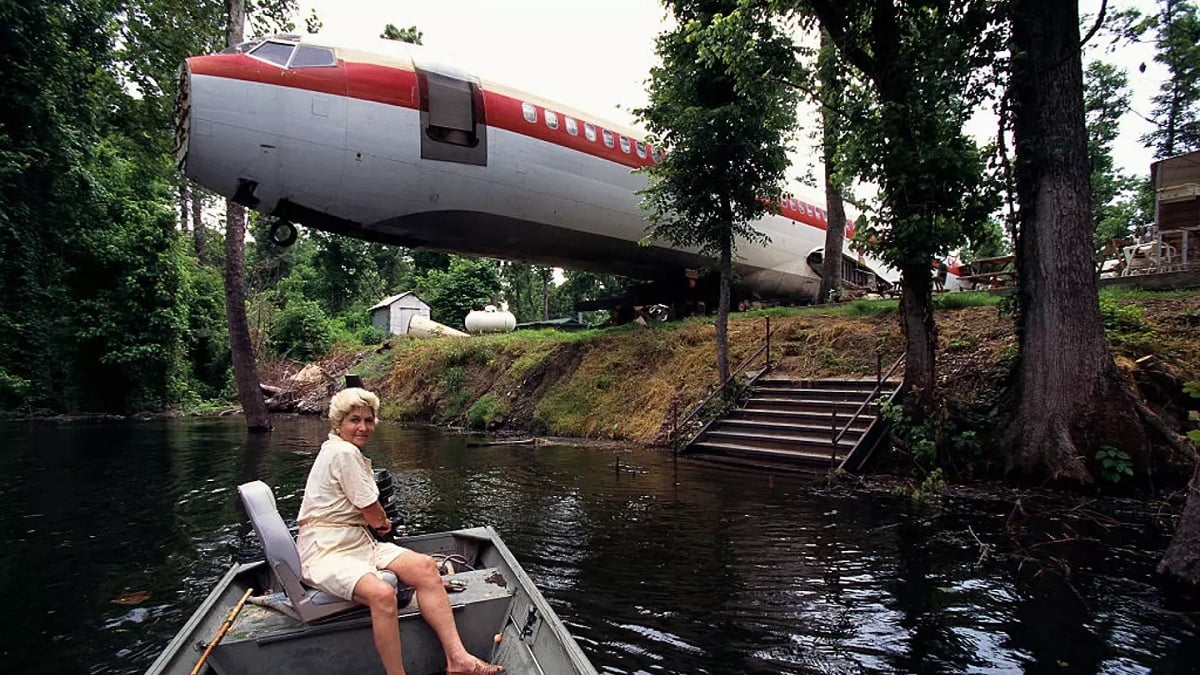 photo montrant la propriétaire sur un bateau au premier plan et son avion rénové en second pl