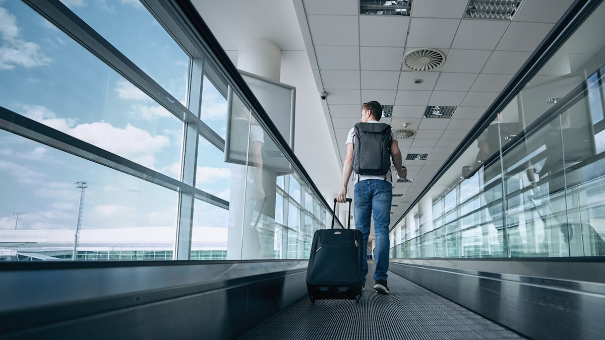 Un voyageur en train de marcher sur un tapis roulant dans un aéroport