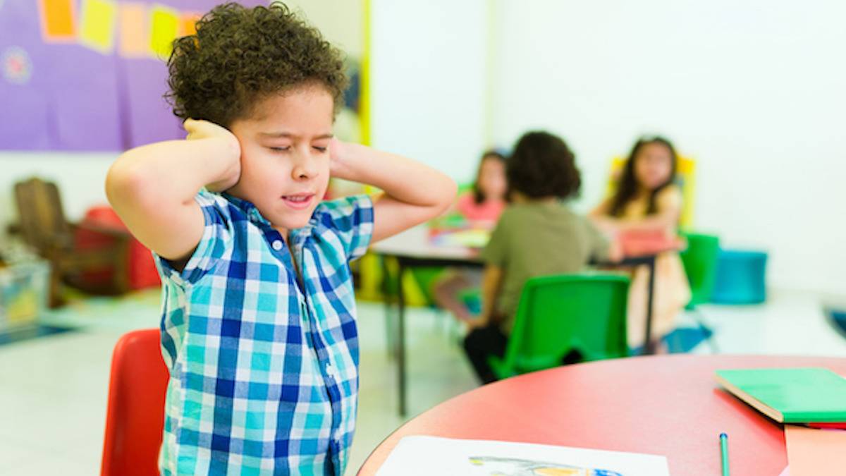 Un élève de maternelle qui se bouche les oreilles  