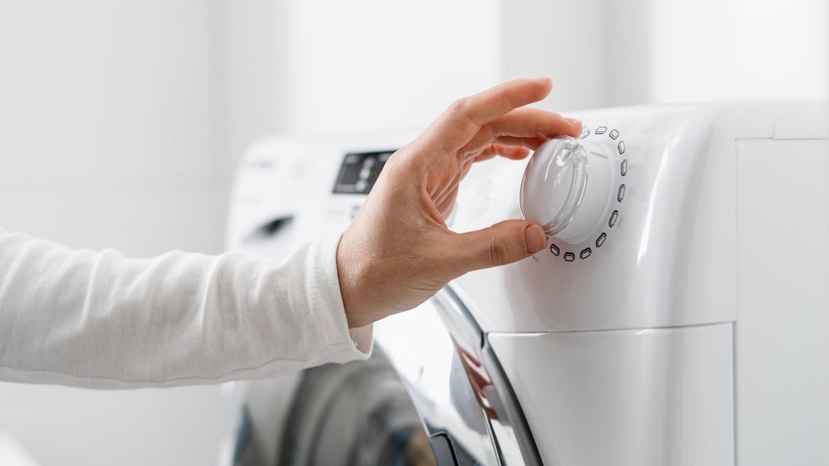 personne choisissant le mode de lavage sur une machine à laver