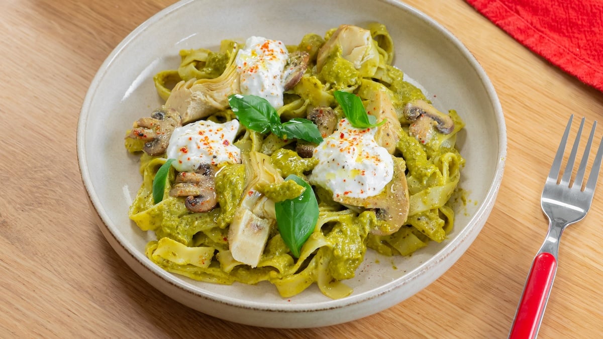 Une assiette de pâtes au pesto crémeux, champignons et artichauts.