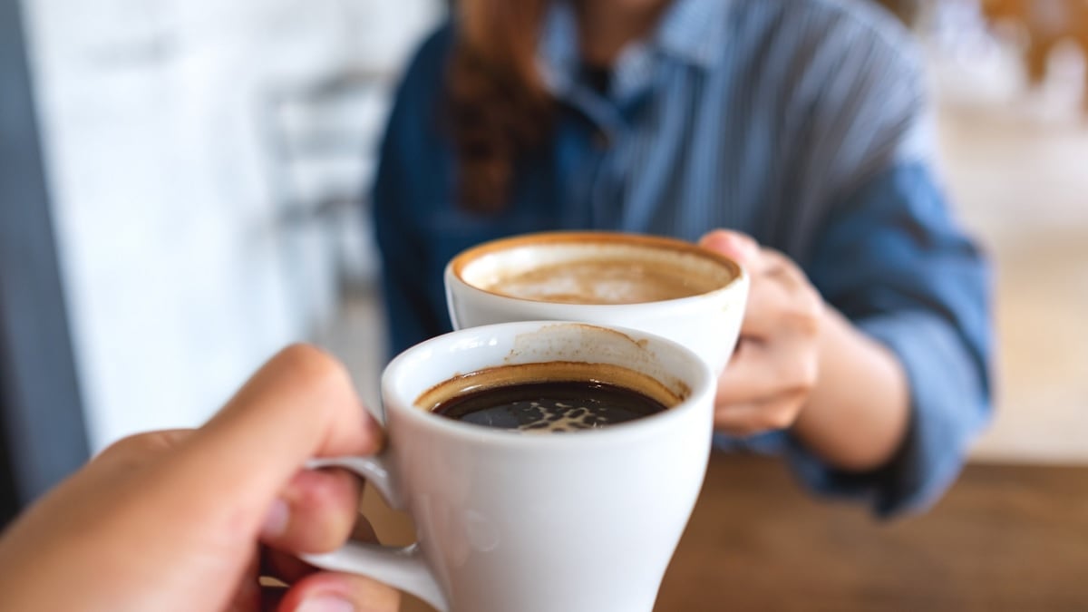 deux personnes trinquant ensemble leur tasse de café 