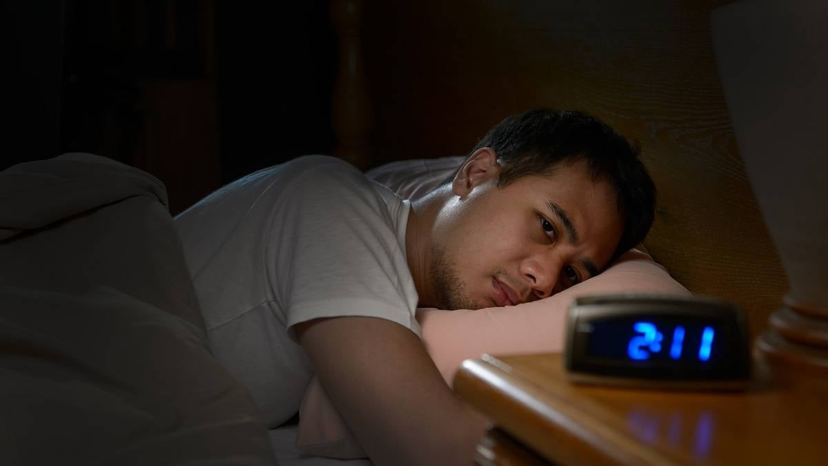 jeune homme souffrant d'insomnie en pleine nuit