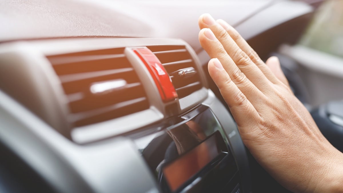 main placée devant les grilles du climatiseur dans une voiture