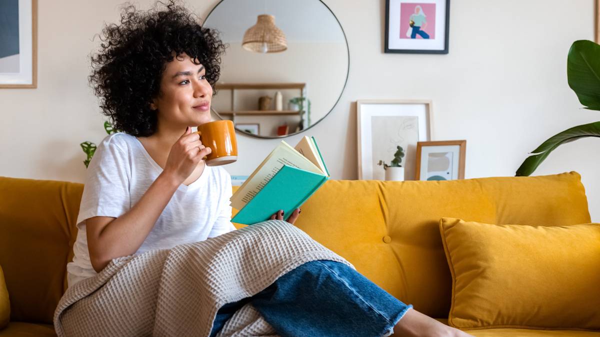 Une femme en train de lire un livre dans son canapé