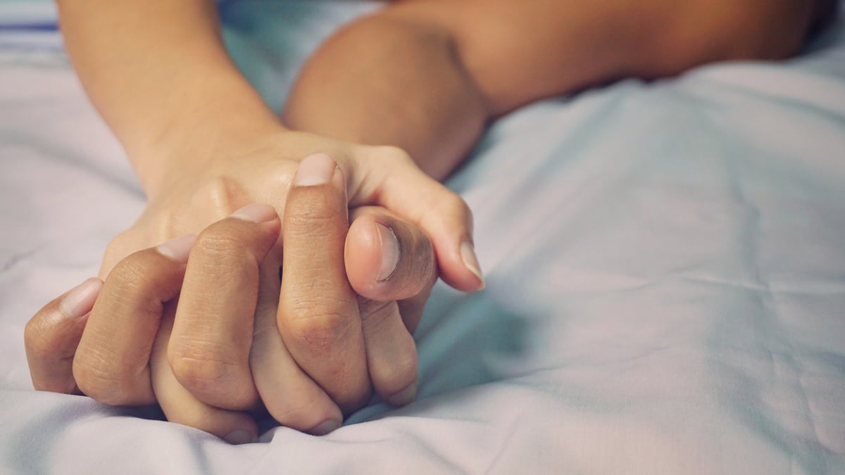 gros plan sur les mains d'un couple au lit