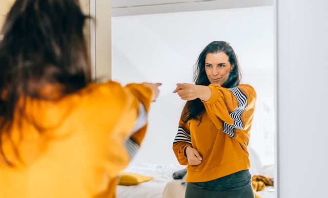 Une femme pointant du doigt son reflet dans le miroir,