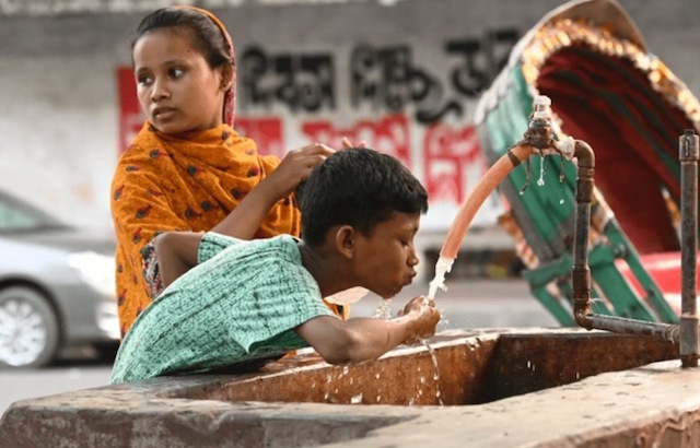 Un enfant qui boit de l'eau au bord de la route 