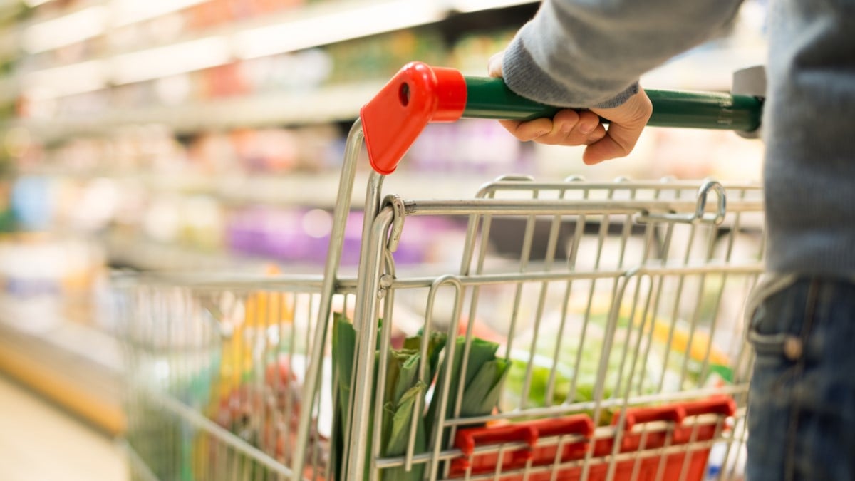 une personne pousse un chariot de courses dans un rayon de supermarché