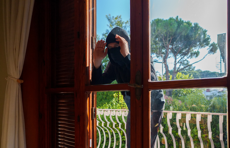 Un voleur regarde par la fenêtre d'une maison