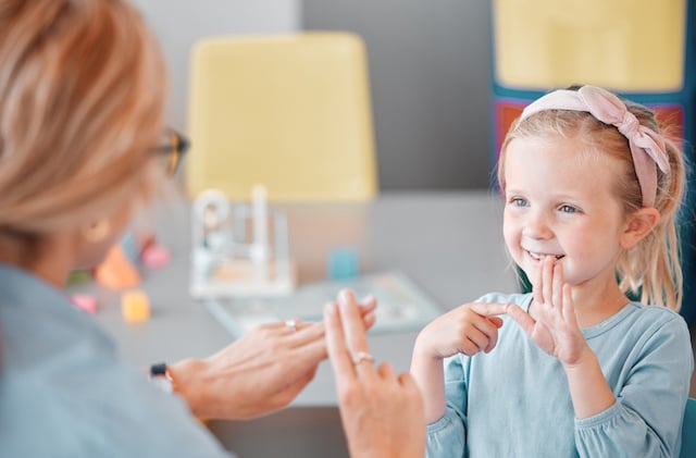 Petite fille qui utilise la langue des signes avec une psychologue pour enfants 