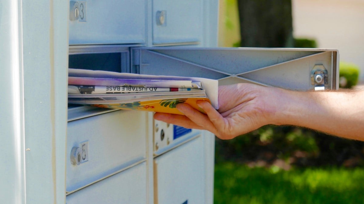 Une personne prend son courrier dans sa boîte aux lettres