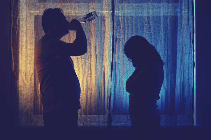 Silhouette d'un couple buvant de l'alcool, derrière une toile de tente