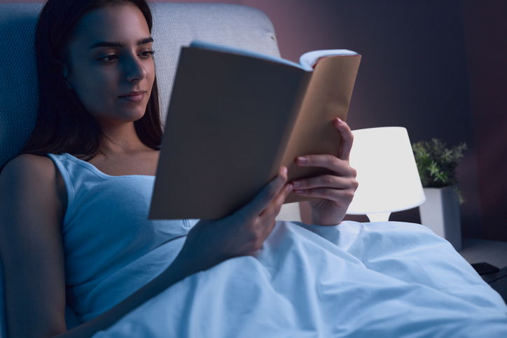 Une femme lit un livre dans son lit