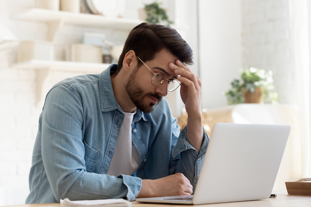 Un homme confus qui regarde l’écran d’un ordinateur portable 