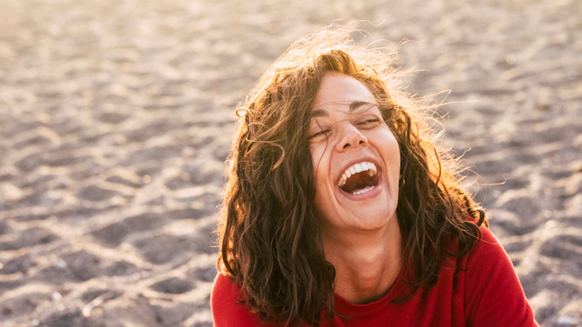 une femme rit d'une blague sur la plage