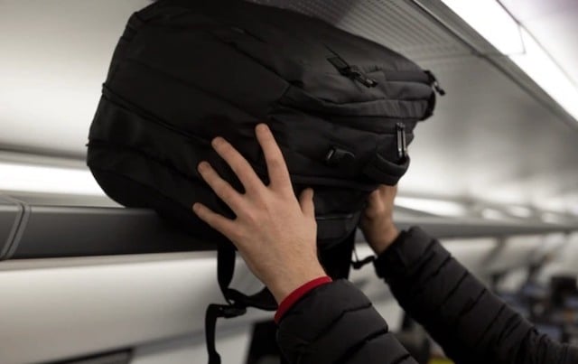 Un homme en train de ranger son sac dans un train