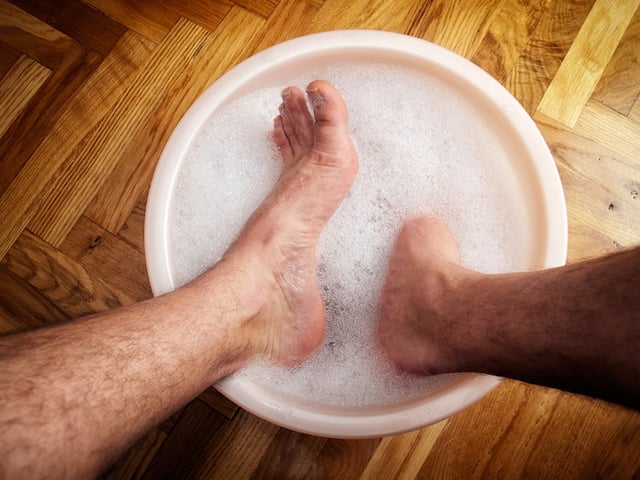 Un homme qui trempe ses pieds dans une bassine 