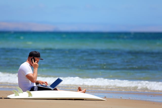 Un homme qui fait du télétravail sur une plage