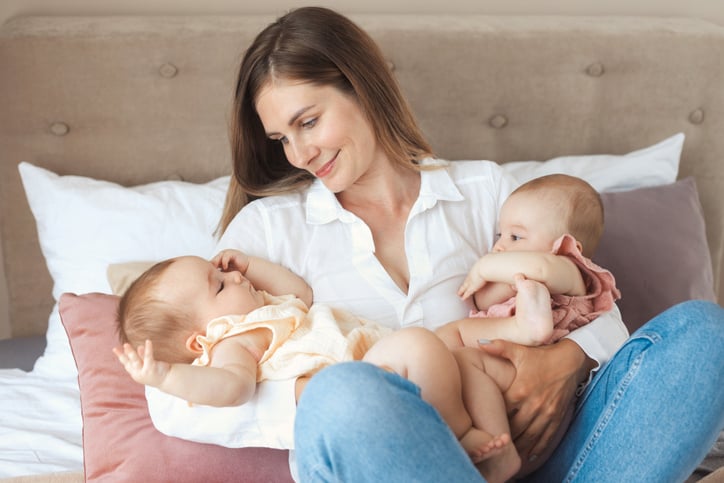 Une jeune mère heureuse tenant deux petites jumelles dans ses bras