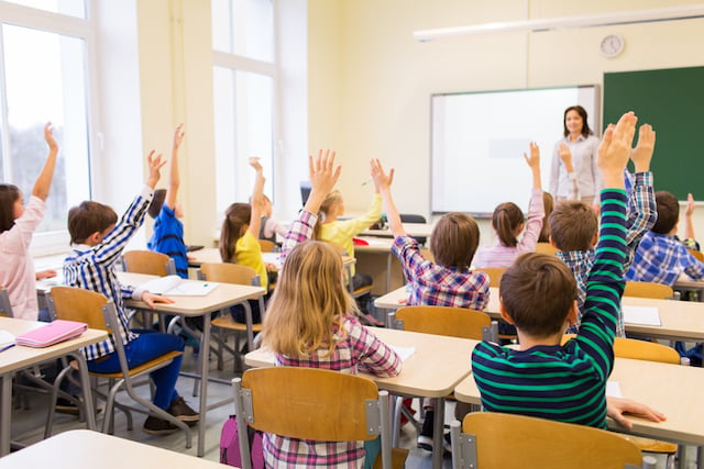 Groupe d'élèves en train de lever la main dans une salle de classe