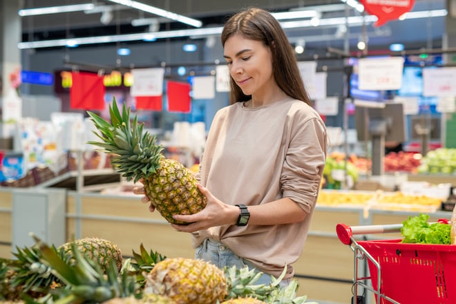 Une femme achète un ananas au supermarché