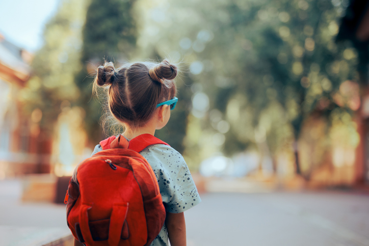 Une petite fille avec un cartable sur le dos