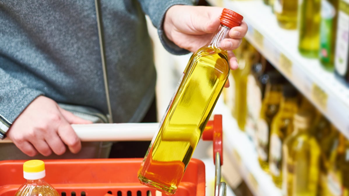 Un homme en train de choisir de l’huile d’olive naturelle ou de l’huile dans un magasin