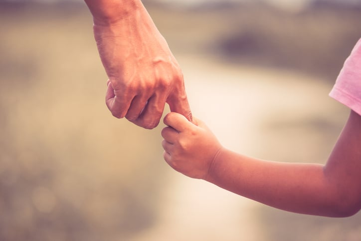 Un enfant tient le doigt d'un adulte