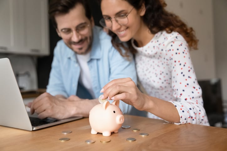 Un couple met de l'argent dans une tirelire