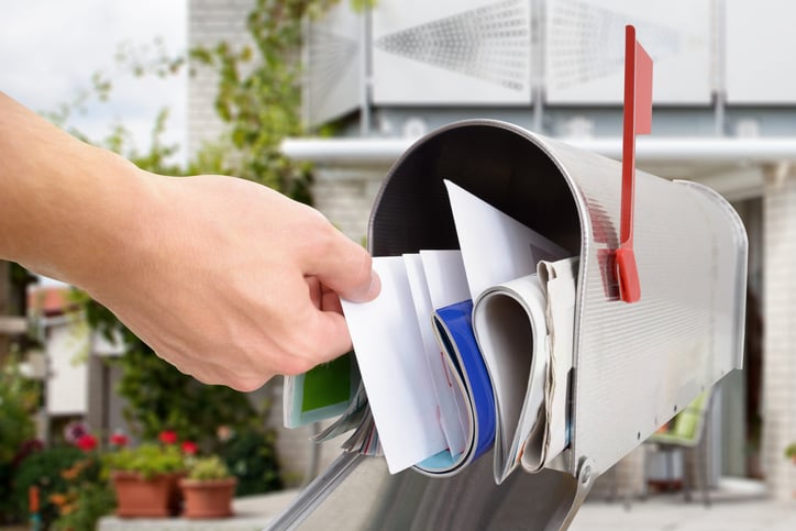 Un homme prend une lettre dans sa boîte aux lettres