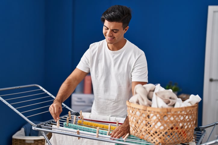 Un homme, souriant, est en train d'étendre son linge propre