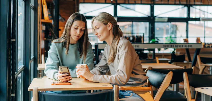 Deux femmes regardent un téléphone dans un café