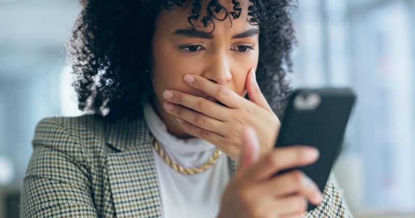 Une femme fronce les sourcils devant son téléphone