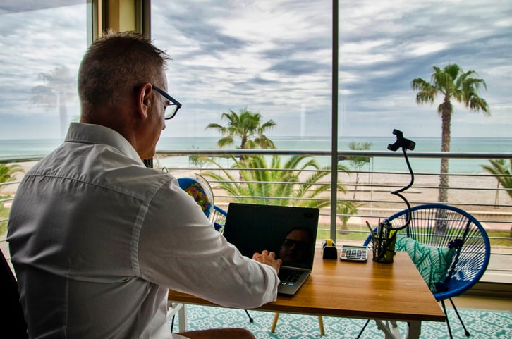 Un homme sur son ordinateur face à la mer