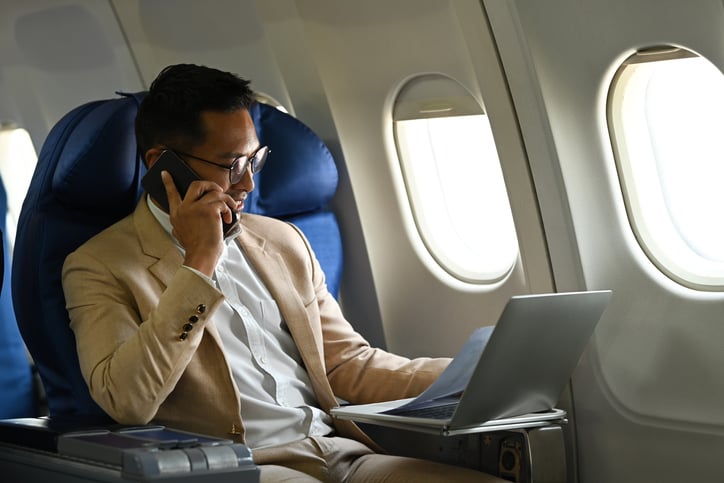 Un homme utilise un téléphone et un ordinateur dans un avion