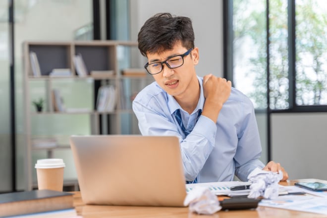 un jeune homme se masse le cou au bureau