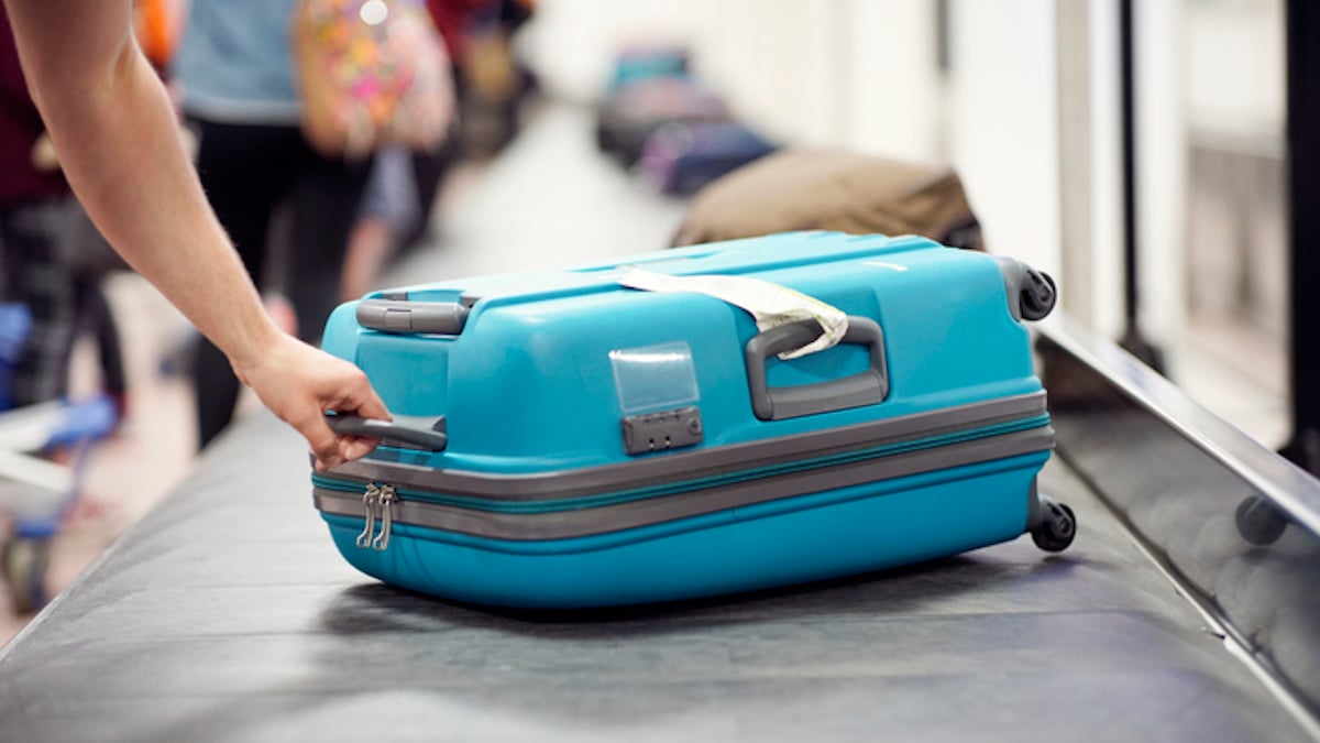 Un voyageur récupère son bagage à l'aéroport