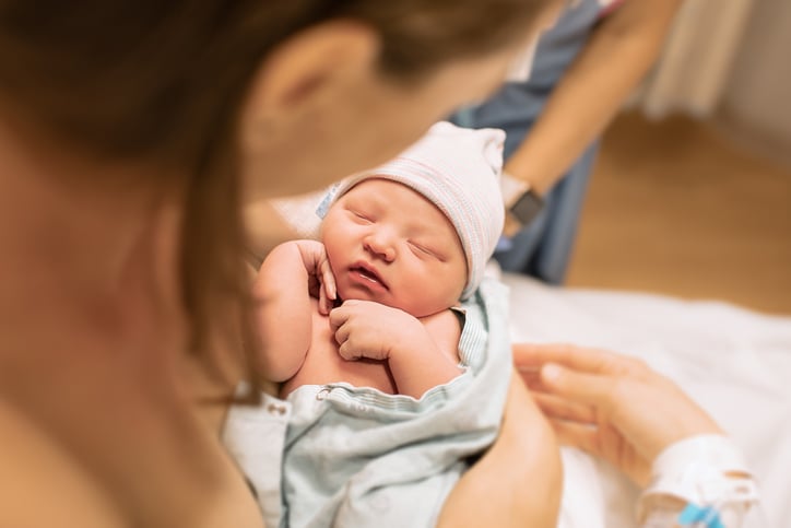 Une jeune maman regarde son bébé qui vient de naître