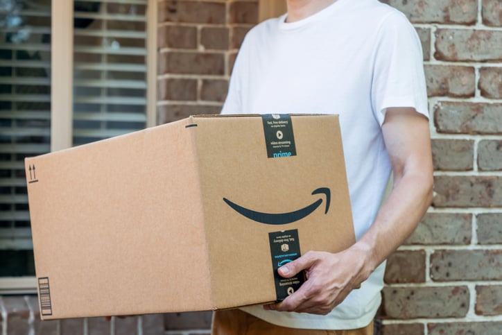 Une personne porte un colis Amazon